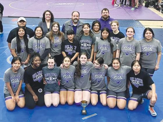 Gilmer High School wrestlers and coaches gather around their third-place trophy from the Division 2 Girls State Duals tournament.