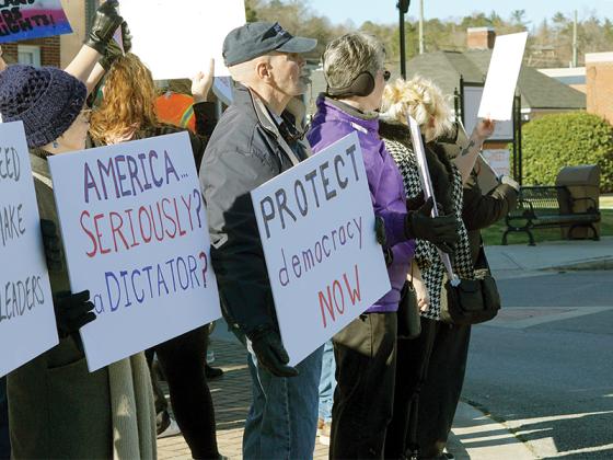 People’s protester Tim Hill holds a sign reading “protect democracy now” while wearing a “make America think again” hat. “Democracy is not dead, it’s not a failed system, it’s alive and strong and we’re here to defend it and propose for it,” Hill said on why he chose to protest on Presidents Day.