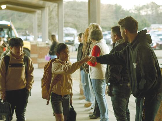 Junior Cash Williams fist bumps 6th grader Jefry Loarca Aguilar as he gets off the bus and heads into Clear Creek Middle School. 