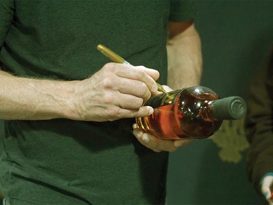 Dierks Bentley autographs bottles of his ROW 94 bourbon crafted in Owensboro, Ky.