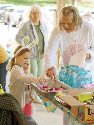 President of Auxiliary Melissa Shedd gives 6-year-old Abigail Cline a cupcake with a peep on it.