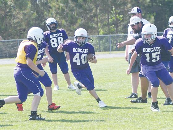 Clear Creek offensive coordinator Taylor Johnstone (right) points to offer an optimal running path midplay at last Friday’s final spring practice.