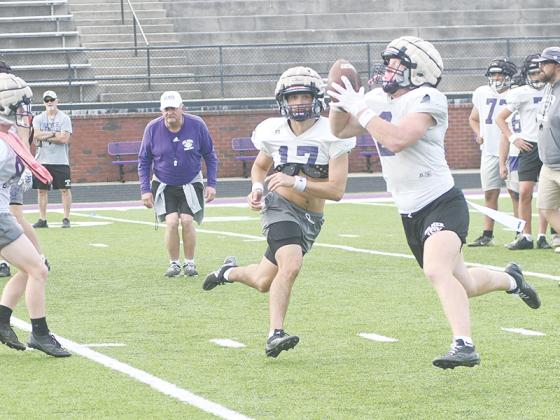 Quarterback Bo Cronic pitches to wingback Douglas Callihan as head coach Paul Standard intently observes.