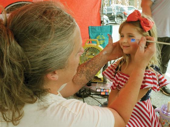 Kelly Gelsomino gets an American Flag painted on her face by Christina Wagner at the Ellijay market. 