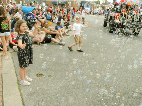 Children try to catch bubbles blown during the July 4 parade.