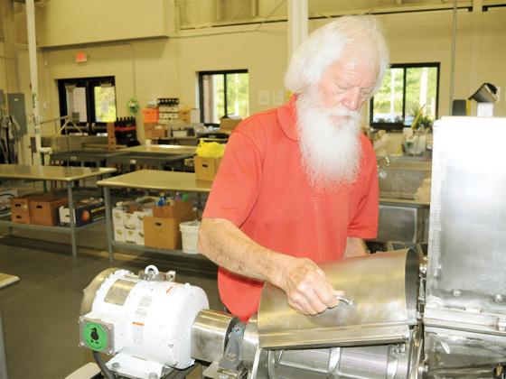 Cannery Supervisor Larry Young examines machinery at the Gilmer County Cannery.