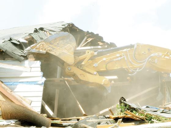 A CAT excavator works to demolish the building on 84 South Main Street.