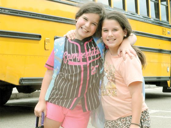 Ellijay Elementary School students Reagan Woody, left, and Kennedy Woody, right, give each other a hug before getting on the bus home from their first Monday.