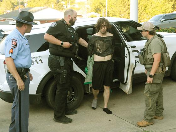 McCayesville police officer Steve Bennett escorts Timothy Craig Ramsey while a Georgia State Trooper and GBI agent look on. (Photo courtesy of the News Observer)