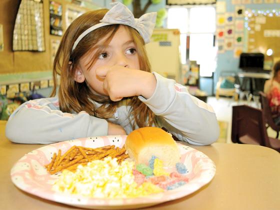 Ellijay Elementary School first-grader Anabella Ledford lines up a full plate of a Charlie Brown Thanksgiving Feast Friday, Nov. 21. The foods she is enjoying are inspired by the classic Charles Schulz “Peanuts” cartoon.