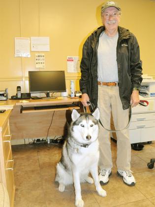 Gilmer Community Food Pantry Director Allen Triebel stands in his office with his husky, Kira.