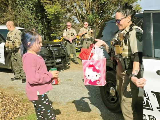 Angel Eaton, left, receives back her Elf on the Shelf, Gumdrop, along with a bag of goodies from Deputy Stacey Weaver, right.