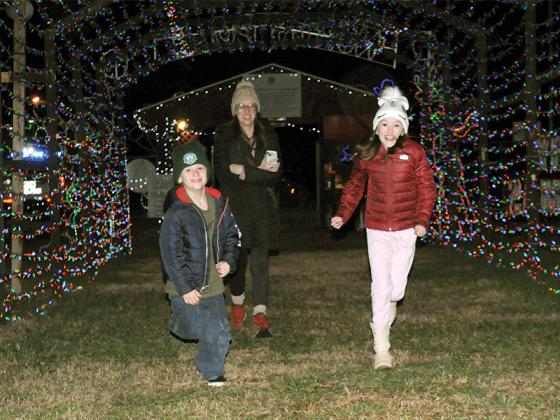 A family rushes into the Ellijay Lions Club’s Holiday Lights of Ellijay 2025. Thousands of Christmas lights made the event special. Shown from left are Jetson Feidler, Sara Mabe and Eyla Mabe.