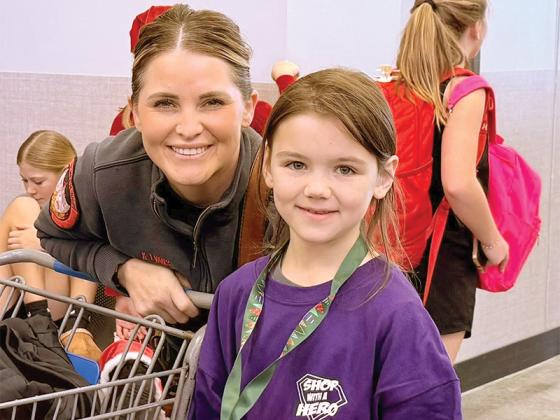 Katherine Evans of Gilmer Fire and EMS, left, and Clear Creek Elementary School student Eowyn Stevenson, right, take their Shop with a Hero trip Saturday, Dec. 13, together to celebrate Christmas. 