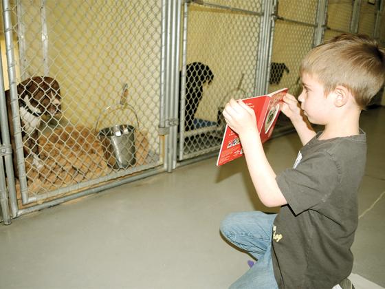 Wyatt Hammond reads a book to Yoshi at the Gilmer County Animal Shelter Monday, Dec. 22.