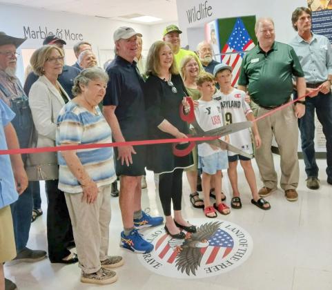 North Georgia Mountains History Center President Jan Murphy cuts the ribbon on her museum with the support of her board members and the Gilmer Chamber of Commerce.
