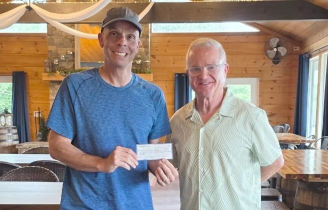 Gilmer Community Food Pantry Director Adam Pilkinton, left, receives $1,000 from Gilmer Pickleball Club President Eddie McDonald, right.
