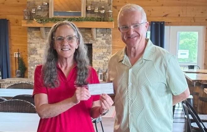 Gilmer Warning Center Co-director Jackie Watson left, receives $1,000 from Gilmer Pickleball Club President Eddie McDonald, right.