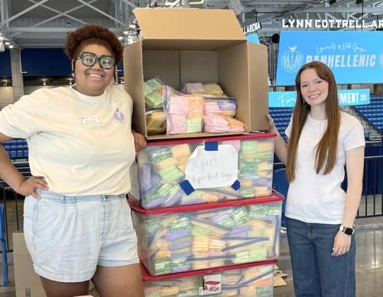 University of North Georgia Assistant Director of Leadership and Community Engagement Emily Harris, left, and Women Together Period Executive Director Emily Slemons, right, stand beside a stack of donated menstrual products.