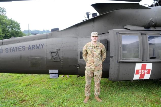 National Guard Sergeant Jacob Brown stands in front of his Blackhawk helicopter.