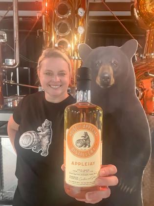 Caroline Porsiel, owner of House of Applejay Distillery, shares some liqueur with one of her business’s bears.