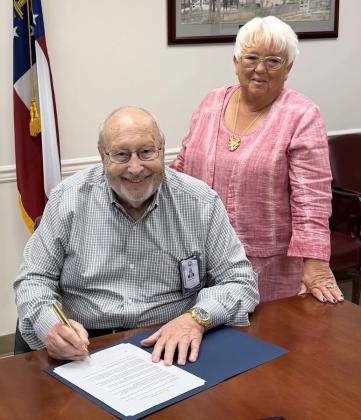 Along with Daughters of the American Revolution Captain James Kell Chapter Regent Danette Ozment, left, Gilmer Board of Commissioners Chairman Charlie Paris, right, signs the America 250 Proclamation for Gilmer County.