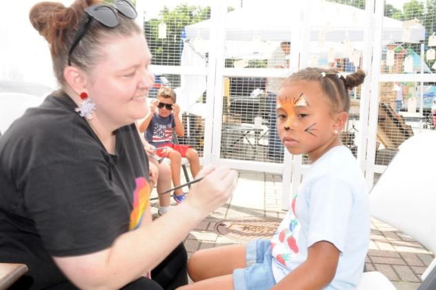 Amy Klassten, left, paints the face of Estrella Davis-Alvarado, right, during July Fourth celebrations in downtown Ellijay.