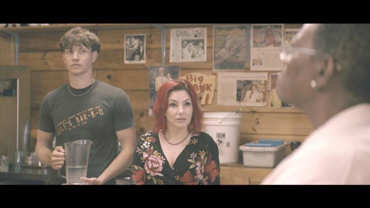 Riley Angel, left, and Poole’s Bar-B-Q owner Candace Sandrini, right, serve a cast member in a scene from “The Breed,” a new horror film made in northern Georgia.
