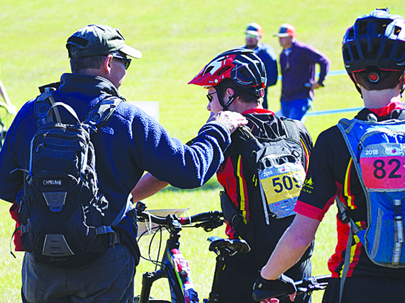 Gilmer Cartecay Youth Mountain Bike Team coach Larry Alonso was selected as one of National Interscholastic Cycling Association’s Coach of the Year recipients. Above, Alonso has some encouraging words for a rider at the start of a race.