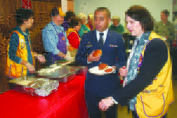 Lion Merle Howell Naylor helps a young cadet from Marietta’s Wheeler High School JROTC program during the annual Veterans Day lunch at the Lions Club. 