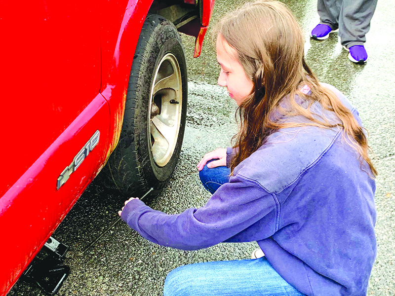 Elise Derck helps change a tire in vehicle repair class.