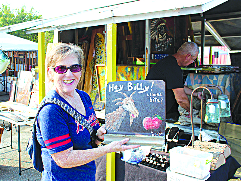 Meg McHale shows off the piece she just purchased from Danny Wilson of Boone Art. “I think the sign goes well with Ellijay and the Apple Festival — it doesn’t get any better than that!” said McHale. 
