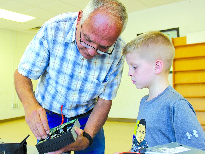 Jaxon Sevcech, 7, watches as volunteer Mickey Moskovitz explains how a DVD disc drawer works. The “Deconstruction Zone” at the Three Rivers Boys and Girls Club is a popular once-a-week class.
