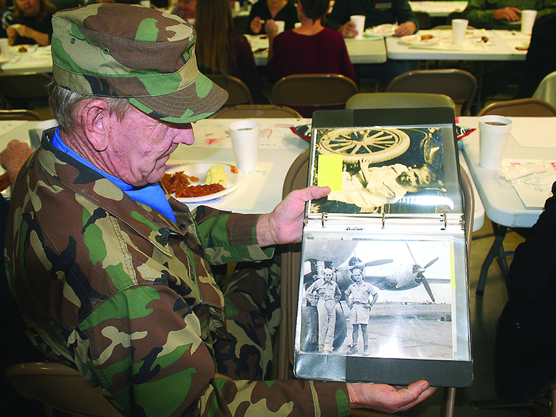 Desert Storm veteran Roy Neville Jr. leafs through a scrapbook of photos that show his dad, World War II veteran Roy Neville Sr., during his time of service.