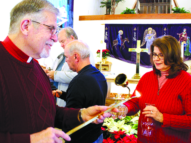 The Rev. David Smedley, left, pastor of Hope Lutheran Church in Ellijay, transfers the Bethlehem Peace Light to the lantern of Marcia Rubin of King of Kings Lutheran Church in Jasper, during a brief ceremony at Hope on Saturday. Rubin and other area church leaders took the lights back to their congregations for Christmas-oriented services Sunday.