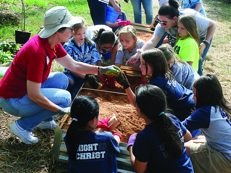 Lisa Harrison, of the Garden Club of Ellijay, left, shows a class at North Georgia Christian Academy how to prepare soil for a raised bed vegetable garden.