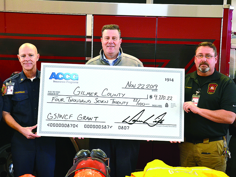 Gilmer County Fire Chief Daniel Kauffman, left, and EMA Director Keith Kucera, right, accept a safety grant check from ACCG representative Joe Dan Thompson. 