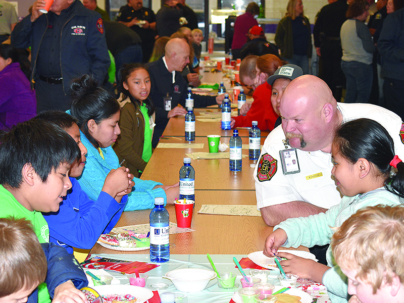 Gilmer Fire and Rescue Deputy Fire Chief Mark Chastain joins kids in a cookie decorating activity at Ellijay Elementary School prior to the Shop With a Hero event.