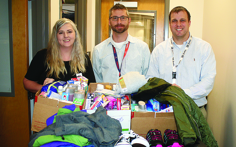 Gilmer High School Assistant Principals Todd Gearhart, center, and Matt Johnson, right, accept Bring a Bundle Clothing Drive donations from Times-Courier typesetter April Teague, left. 