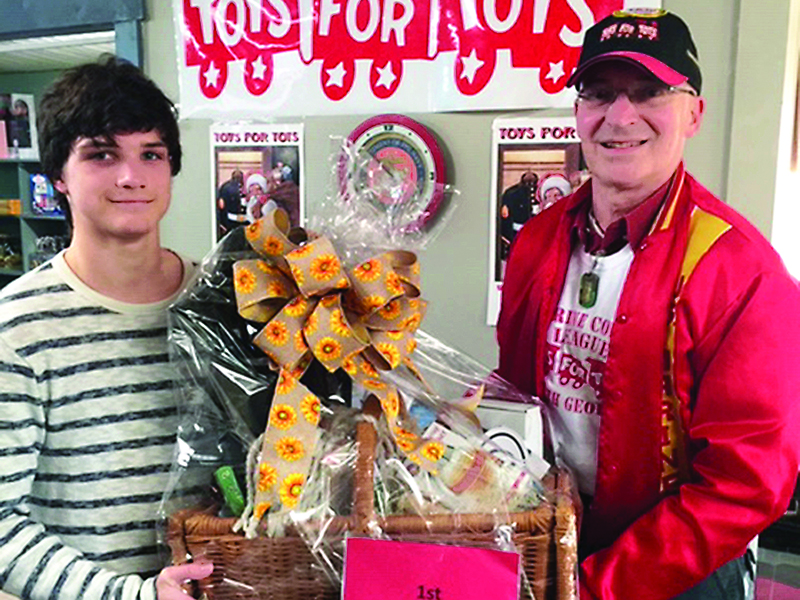 Local Toys for Tots campaign coordinator U.S. Marines Sgt. A.J. LeCompte, right, presents a gift basket to first-place raffle winner Matthew Dean. The raffle helped raise funds needed to carry out this year’s toy drive.