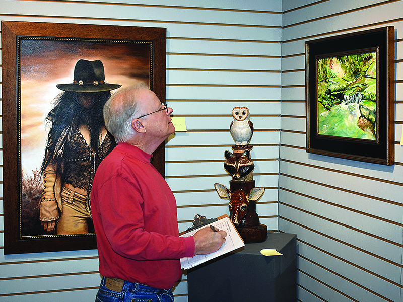 Art show judge Keith Burgess takes a close look at entries in the 2020 spring juried exhibition currently on display at the Gilmer Arts Gallery.