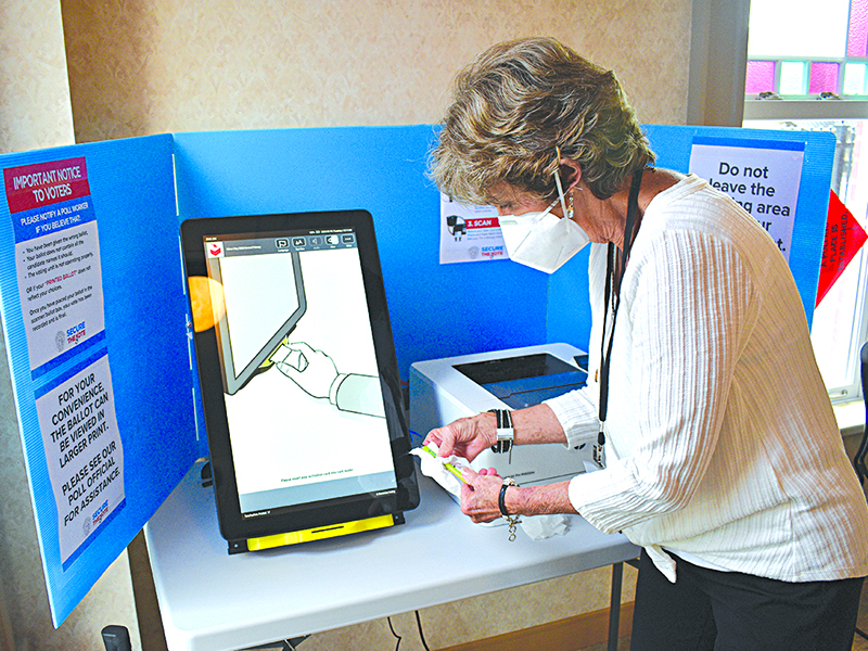 Cathy Tankersley cleans the voting machines and stylus pen during early voting Tuesday, May 19, at the Gilmer County Courthouse. (Photo by April Teague)