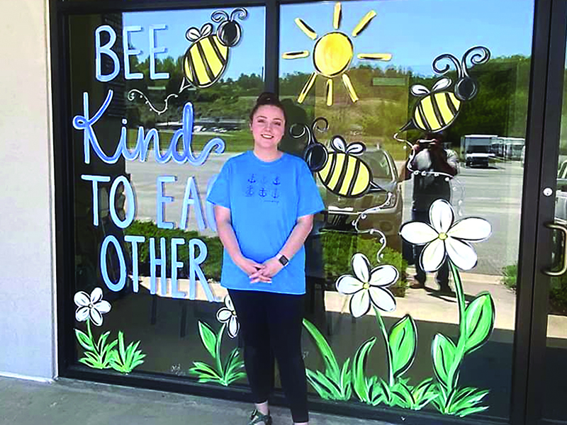 Abby Dotson is pictured in front of a mural she painted in the window of Double L Restaurant. 