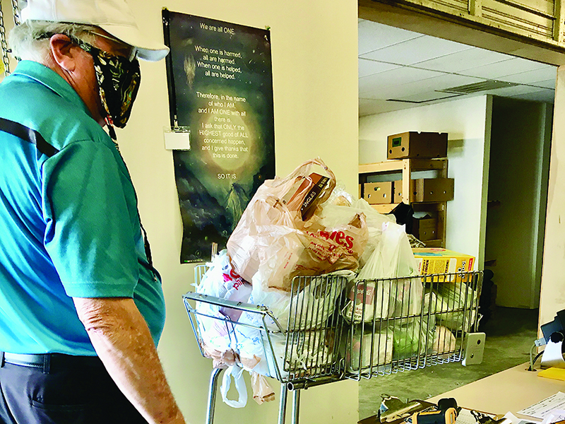 Paul Bryant, a  volunteer at the Gilmer Community Food Pantry, weighs a cart of groceries that is representative of the amount of food families typically receives each Wednesday.