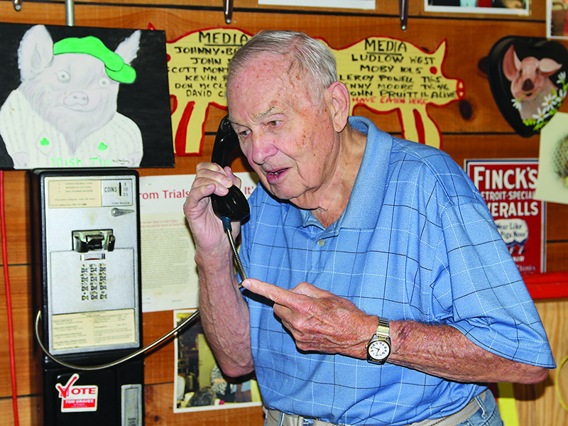The humorous side of Oscar Poole is shown in this photo as the restaurant owner pretends to take a call on an out-of-service payphone at Poole’s BBQ. “He was a humorist who liked to joke and tell stories,” said the photographer, George Winn.