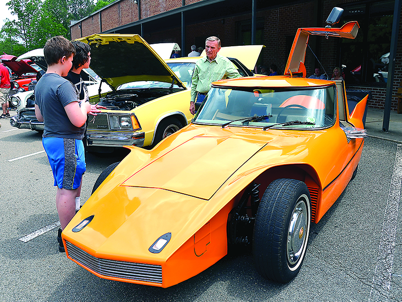 Larry Davis shows the XP-1, a unique car he designed and built, to two curious students during the 2017 Car Show for Kids at Gilmer Middle School.