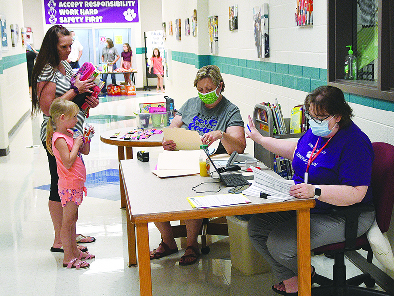 Students from around the county made their way back to schools last week to collect their belongings and visit with teachers.  Above, media specialist Jennifer Painter (in purple) and media paraprofessional Susan Sanford distribute summer reading rewards.