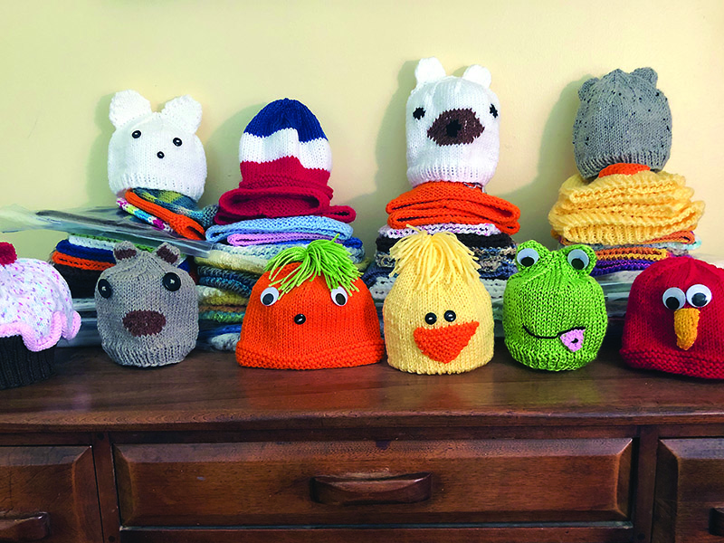 Some of the hats Adelsperger has completed since she started the knitting project in February.