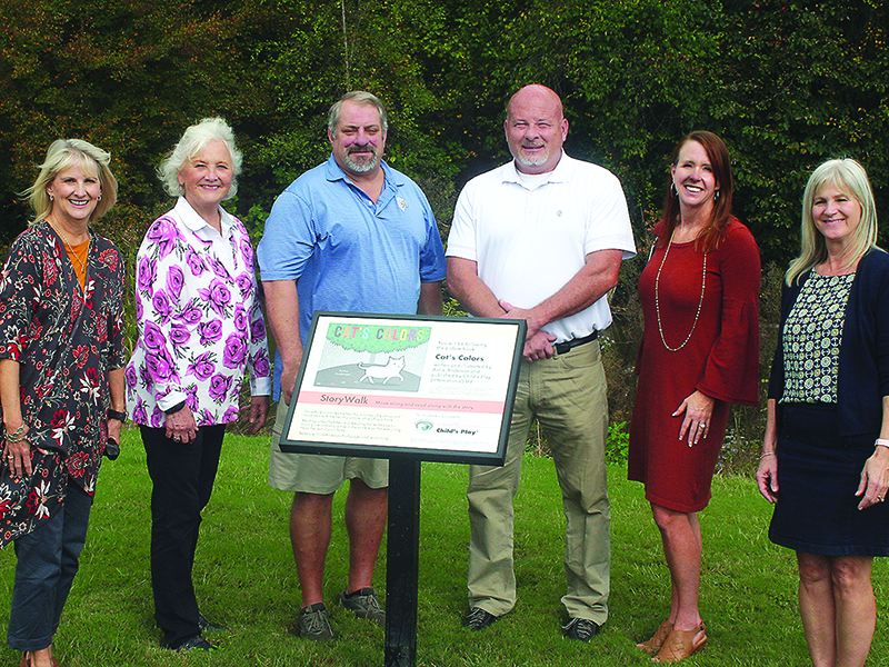 Representatives from Gilmer County Charter Schools and the Gilmer Parks and Rec Department are pictured beside one of the 20 display markers that comprise a new children’s storywalk at River Park. From left: Lottie Mitchell, (school system chief academic officer), Kathy Stephens (B-5 literacy committee member), Kevan White (parks and recreation director), Bob  Sosebee (school system maintenance director), Dr. Shanna Downs (school system superintendent) and Katrina Kingsley (school system pre-K director).