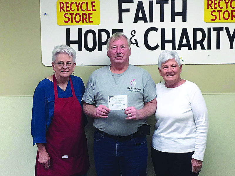 Junior Manley, pastor of By His Grace Independent Church, center, holds one of the meal certificates being provided to several local churches by Faith, Hope and Charity Recycle Store Inc. Also pictured are Faith, Hope and Charity board chairwoman Cheryl Worley, left, and Ellijay First Baptist Church representative Lou Summers, right.